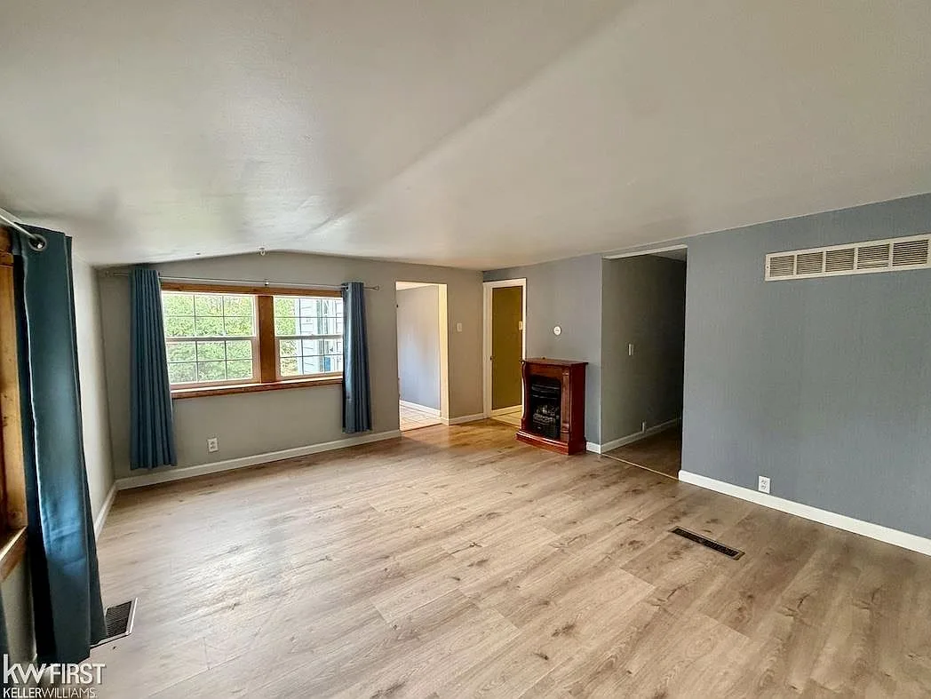 Living room with light wood-look laminate flooring, gray walls, and natural daylight