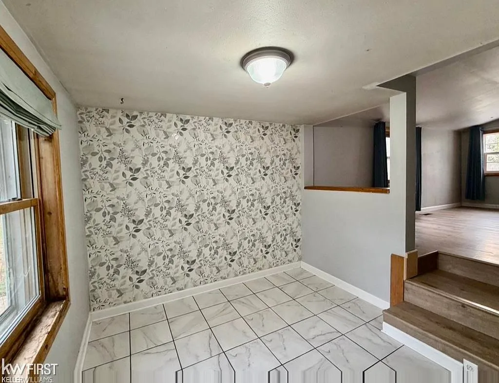 Transition area with tile flooring, steps, and floral-patterned wallpaper feature wall