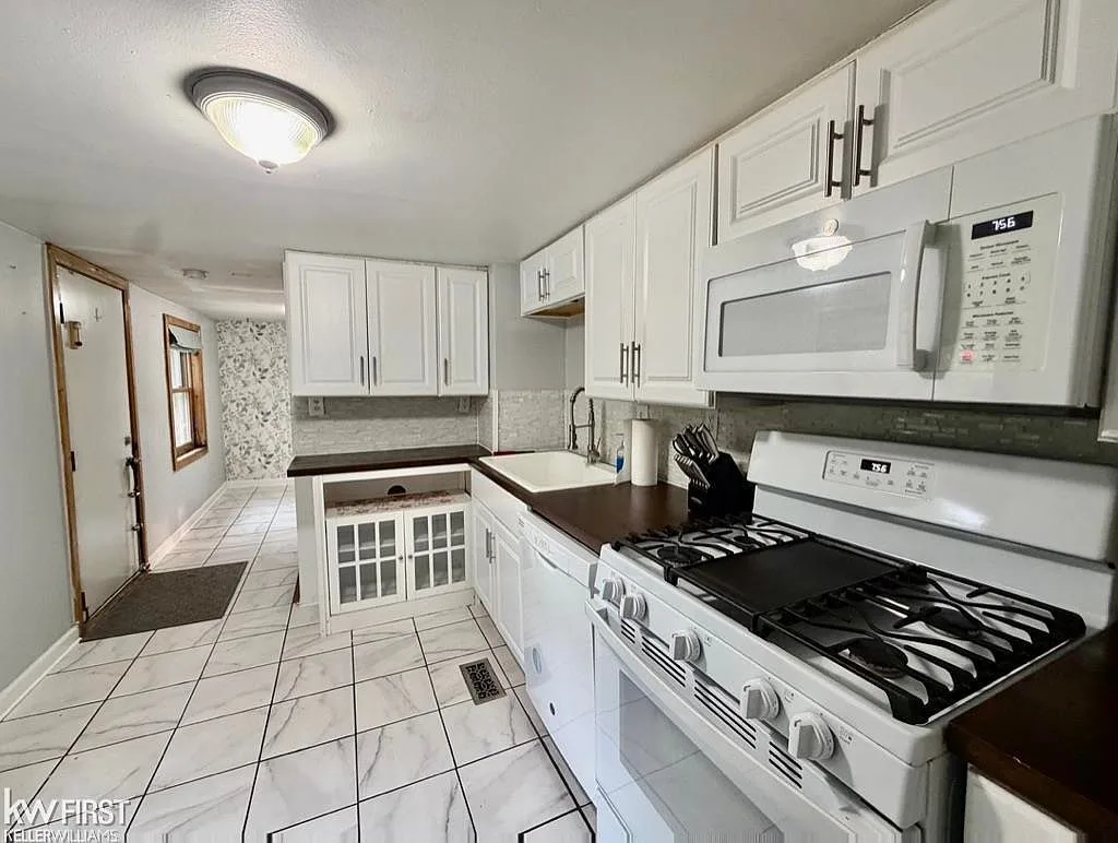 Kitchen with white shaker cabinets and dark countertops