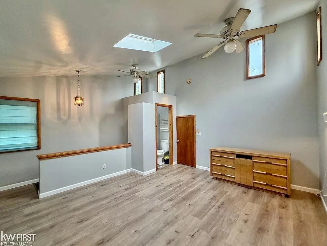 Upper-level primary suite with vaulted ceiling and skylights