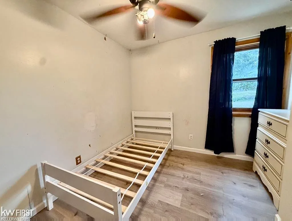Secondary bedroom with wood-look plank flooring and natural window light