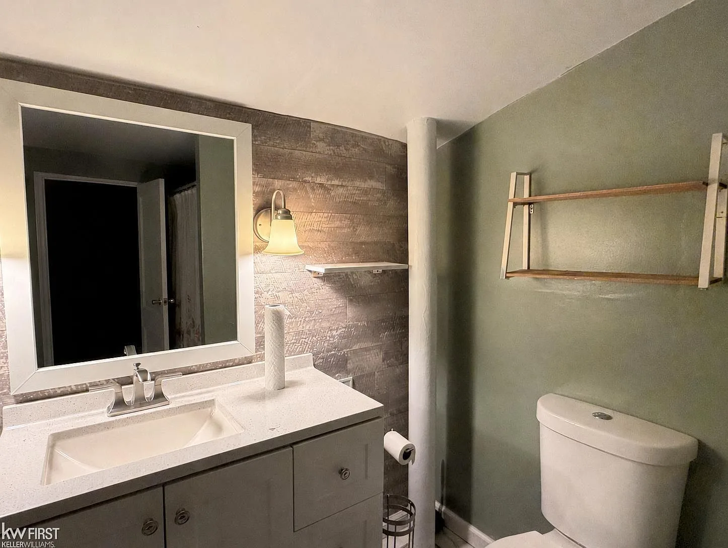 Bathroom with sage green walls, light wood-plank accent wall, and white vanity