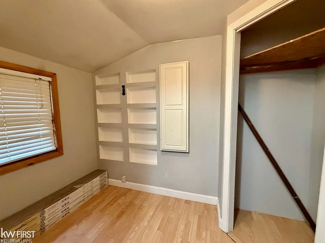 Bedroom with built-in recessed wall shelving, light gray walls, and hardwood flooring