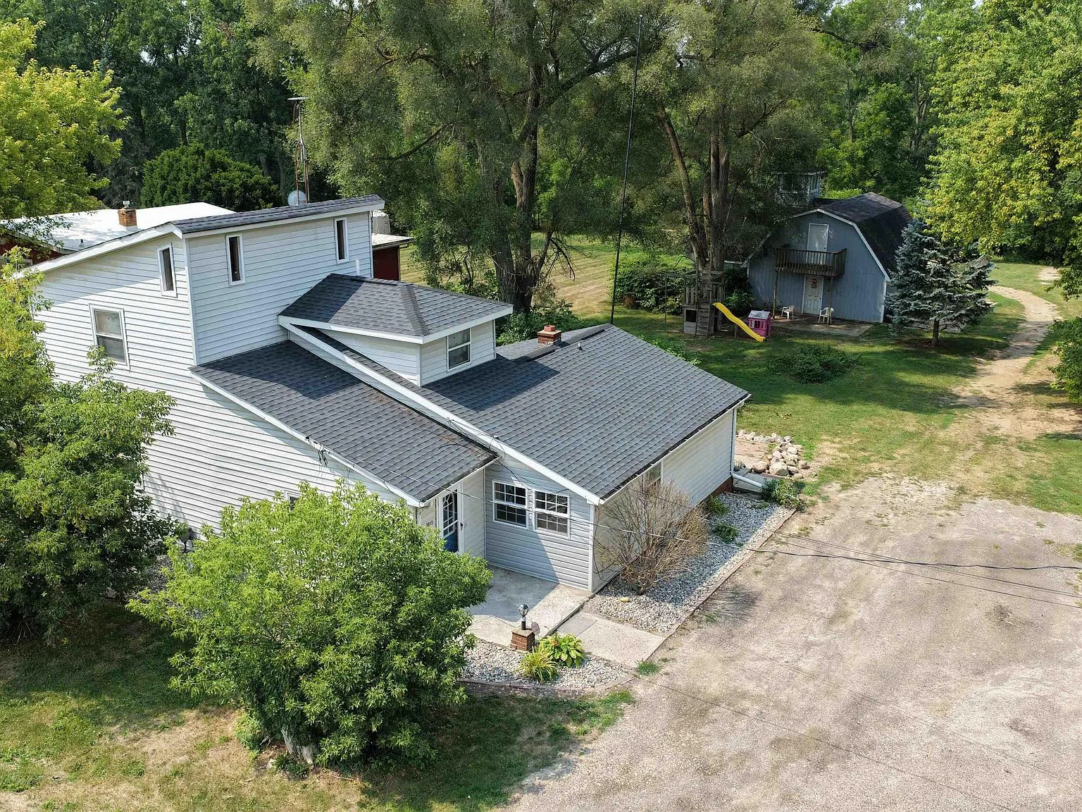 Aerial view of 3049 Egleston Ave showing the home, detached garage, and wooded 0.87-acre lot