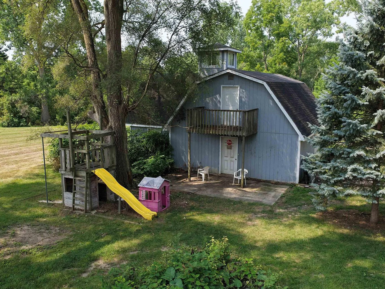 Detached studio/flex building exterior with blue siding, deck, and upper loft area