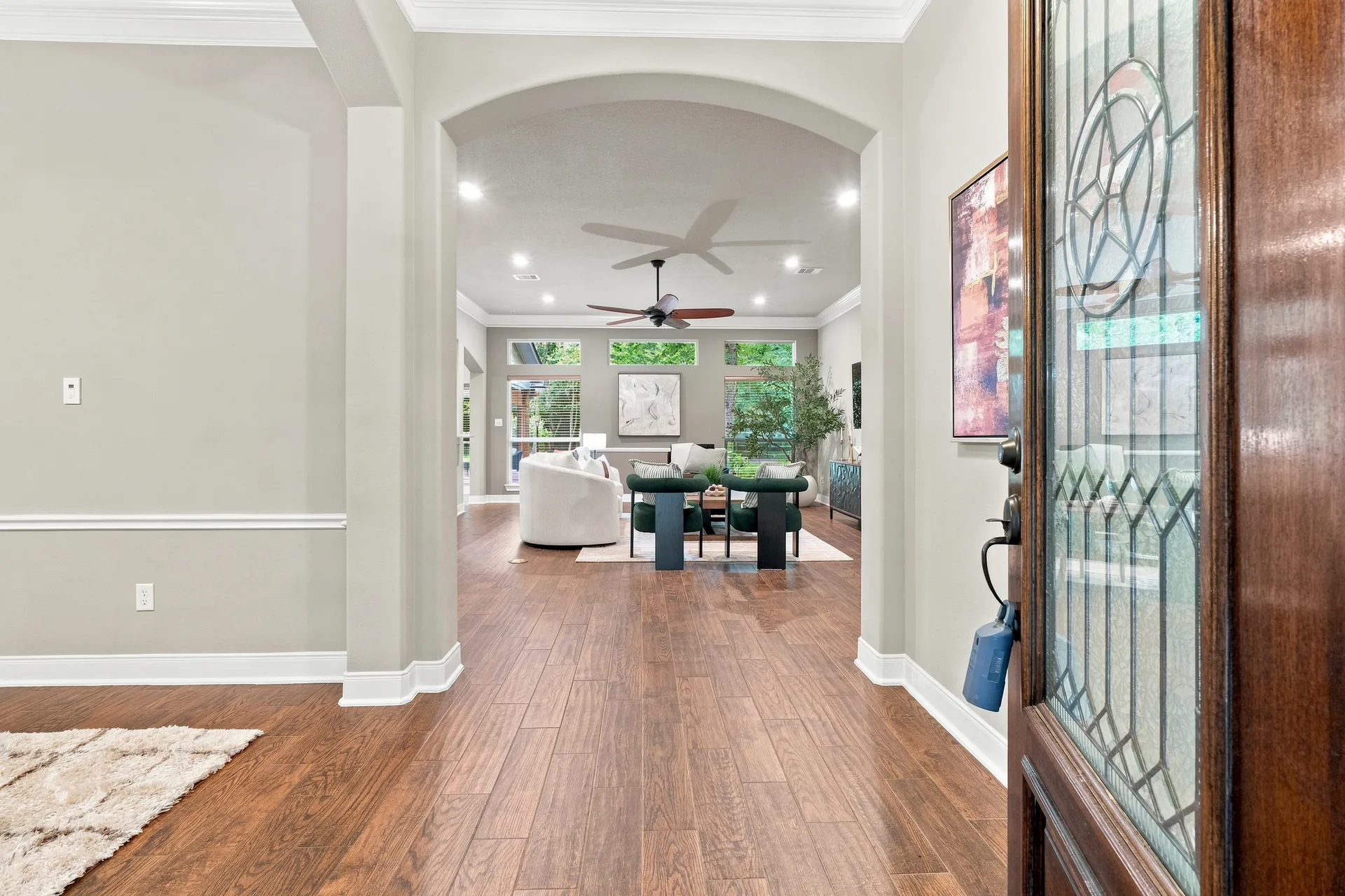 POV looking into the home from the front entrance with arched doorway and hardwood floors