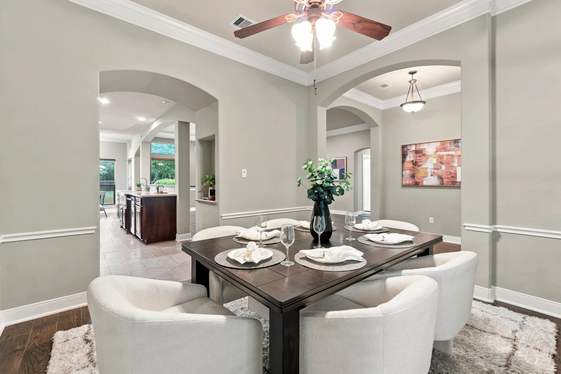 Dining room with arched room transitions, crown molding, and hardwood flooring