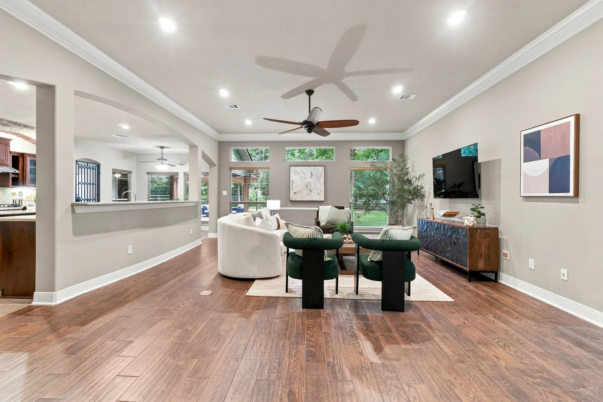 Open-concept living room with dark hardwood floors, neutral walls, crown molding, and recessed lighting