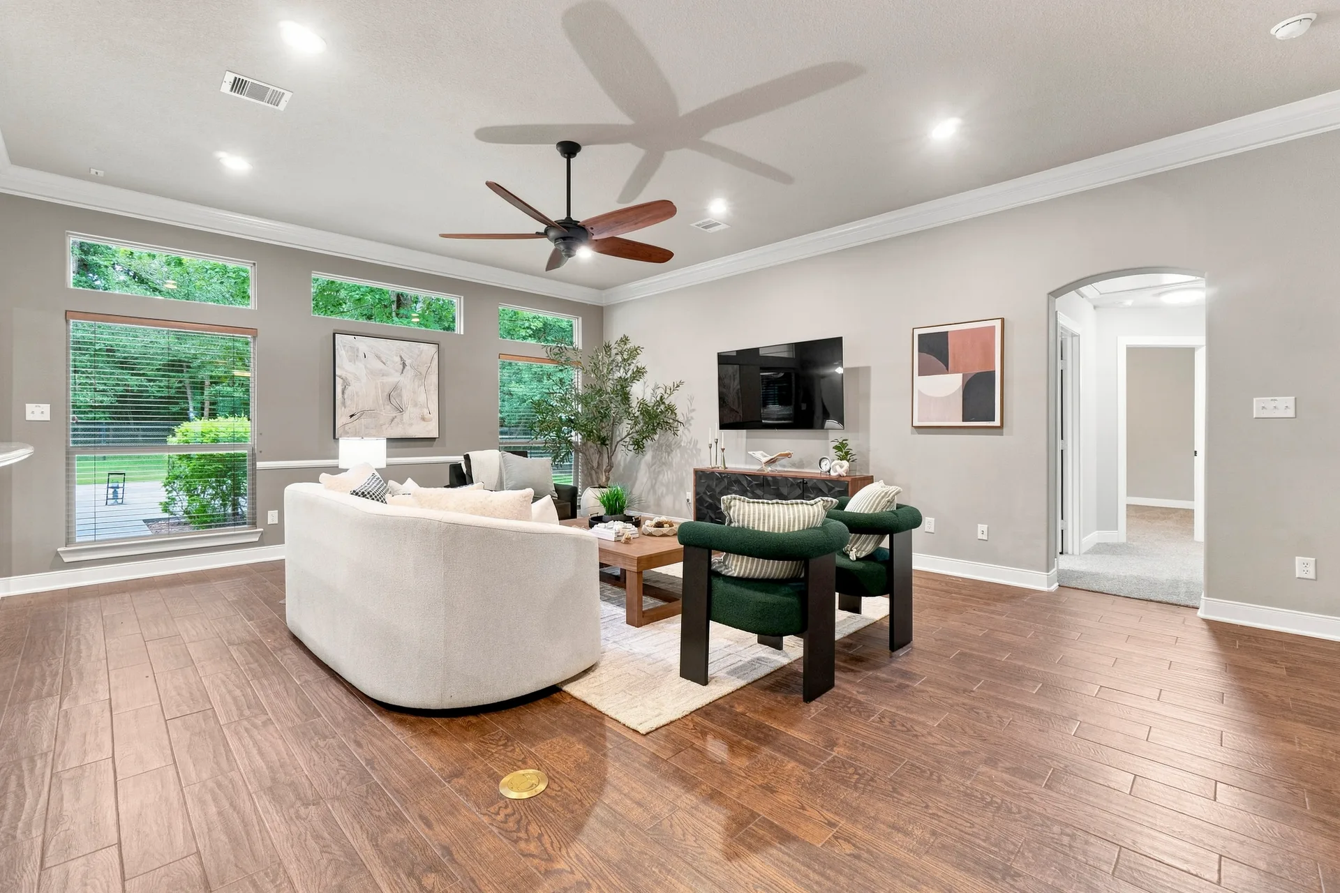 Spacious living room with light gray walls, dark wood-look tile flooring, and natural daylight
