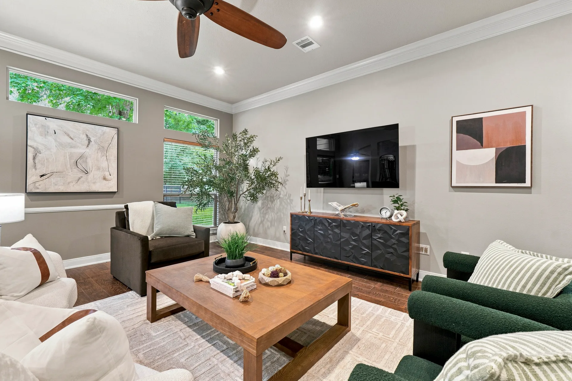 Living room with high ceilings, crown molding, hardwood floors, and open sightlines