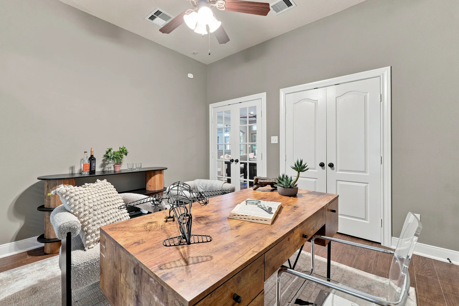 Home office den with grey walls, dark wood-look floors, and ceiling fixture lighting