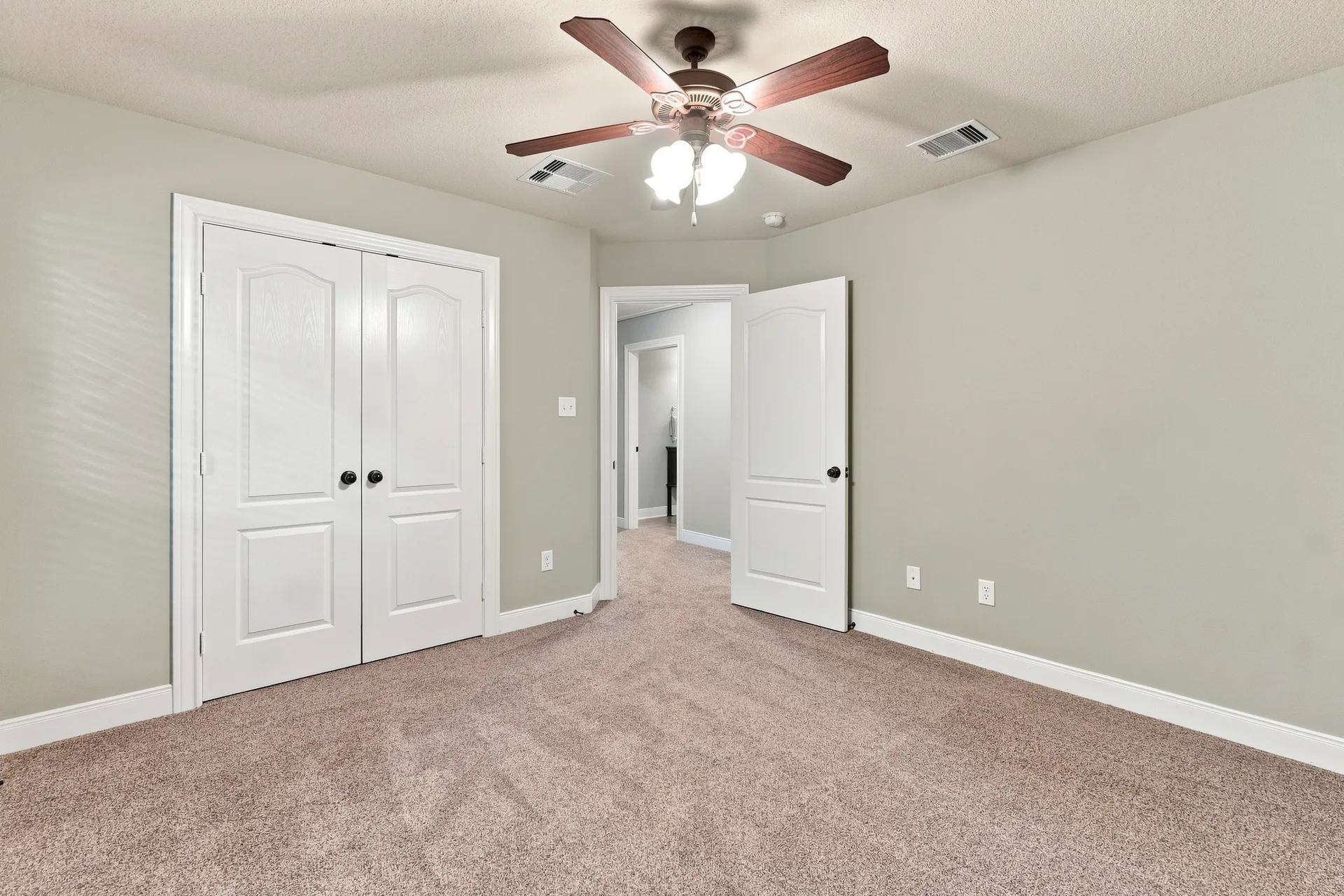 Guest bedroom with light grey walls, beige carpeting, and bright indoor lighting