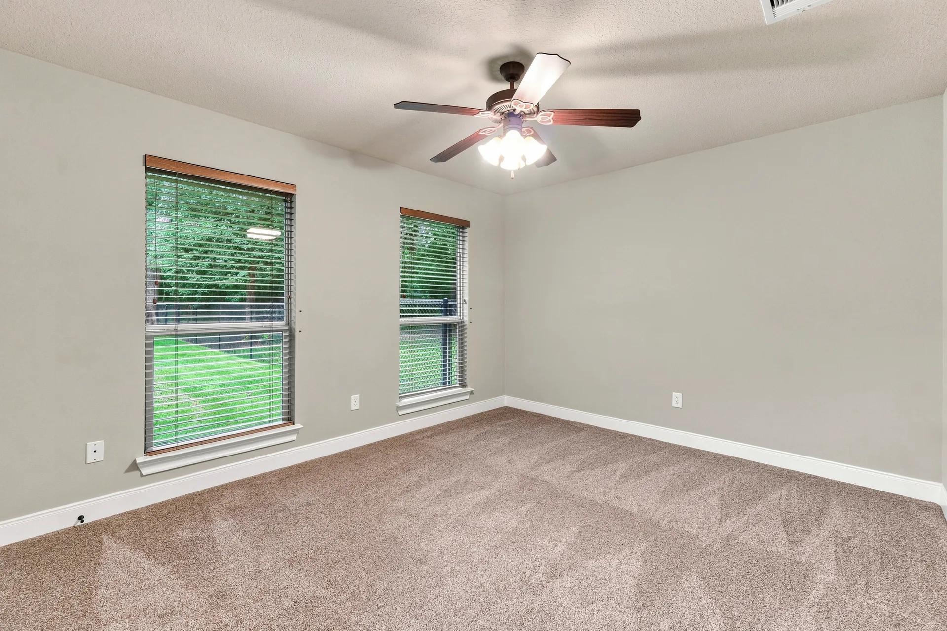 Secondary bedroom with neutral walls, carpeted flooring, and bright natural light from two windows