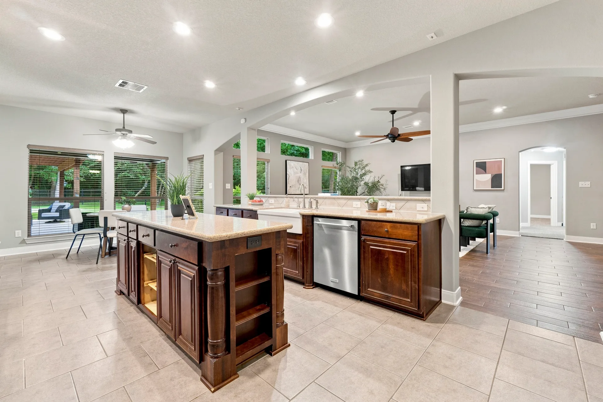 Open-concept kitchen transitioning to living area with dark wood cabinets, granite countertops, and tile flooring