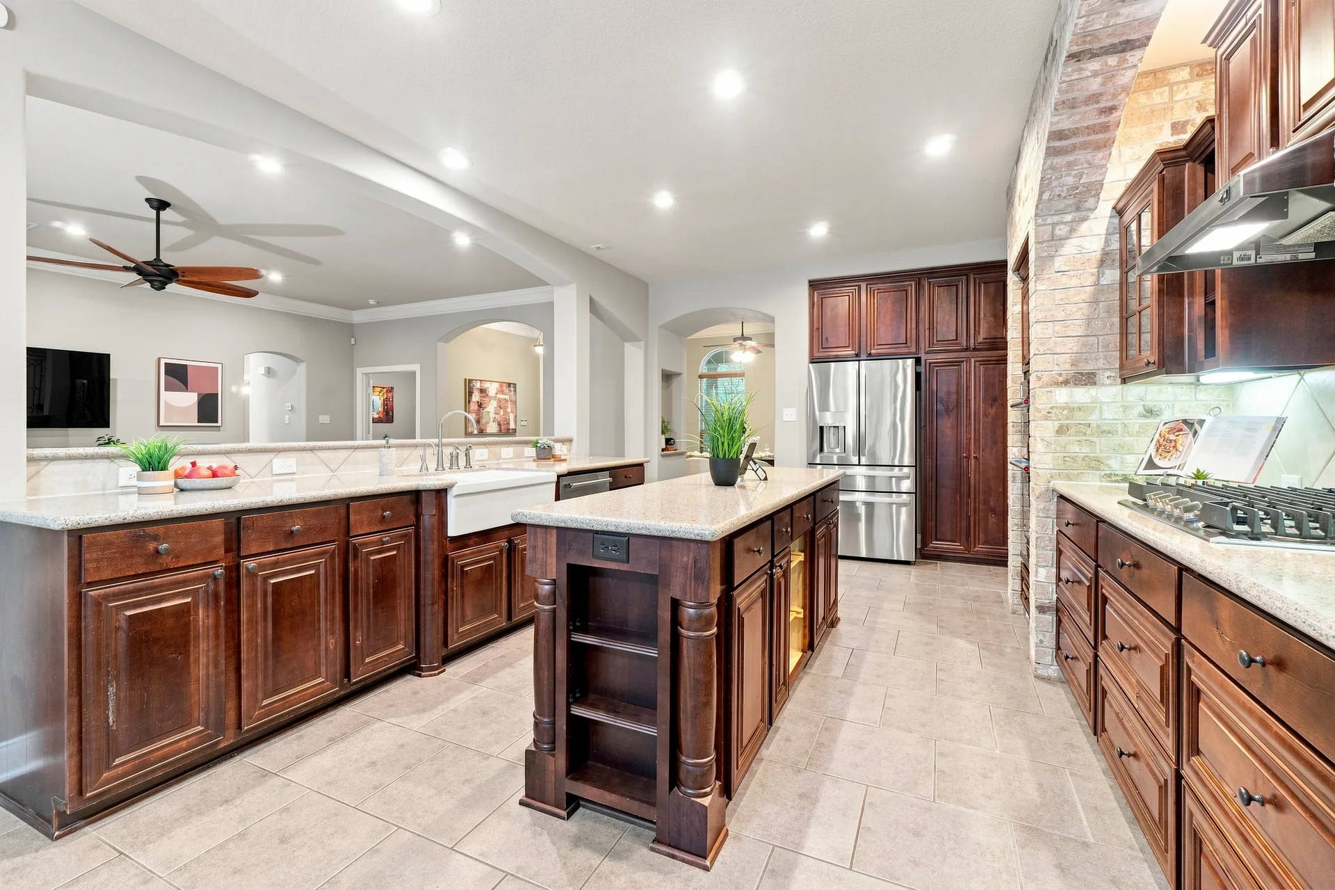 Traditional kitchen with dark wood cabinetry, granite countertops, brick accent wall, and stainless refrigerator