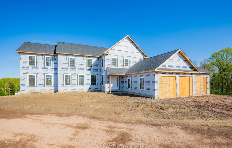 Exterior of colonial home under construction with house wrap