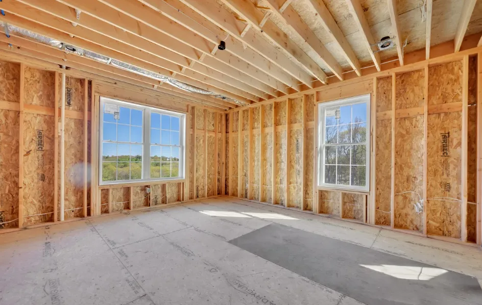 Unfinished bedroom with exposed framing and double windows