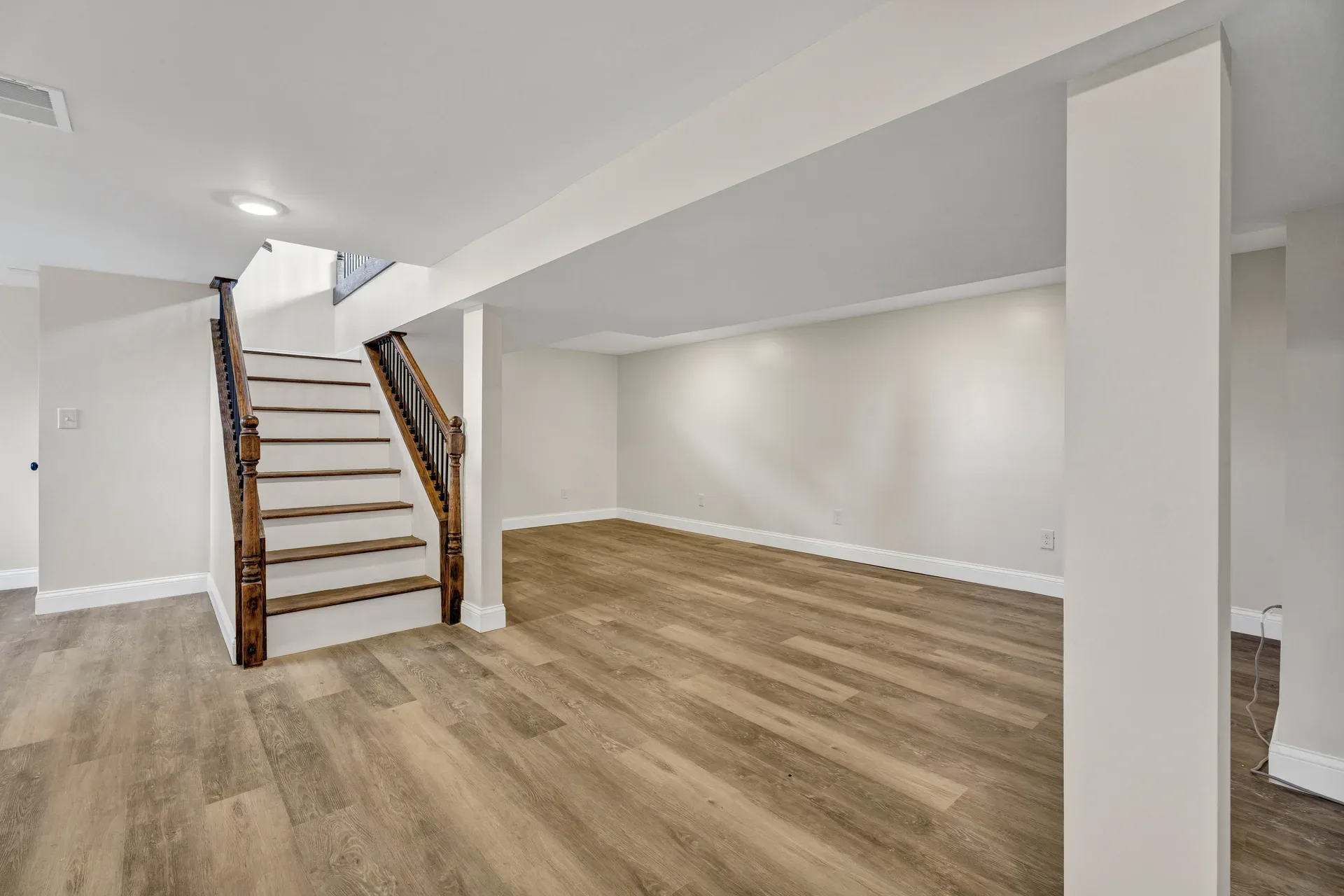 Finished basement recreation room with stairs and recessed lighting