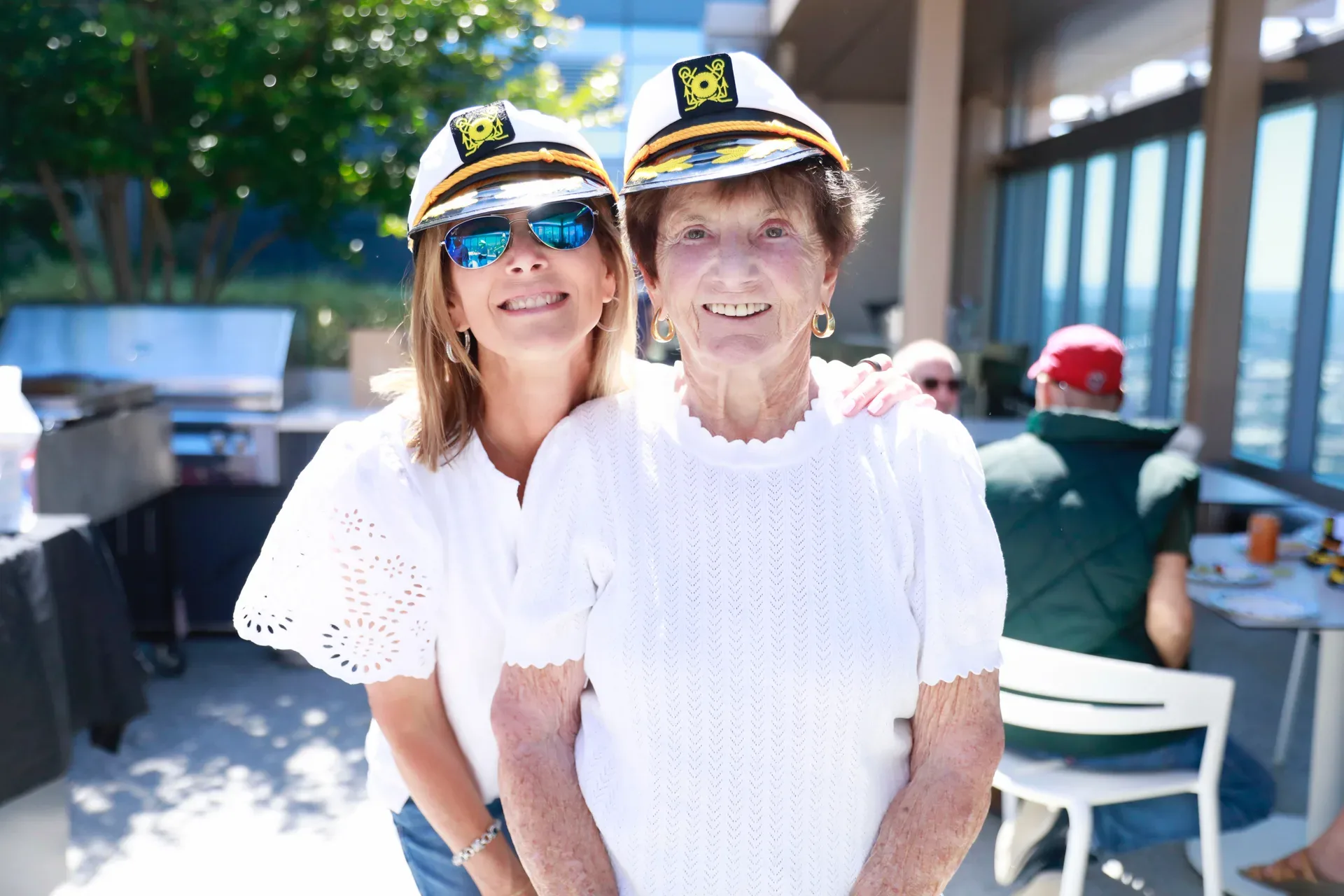Two women in captain's hats enjoy a sunny day on a rooftop terrace