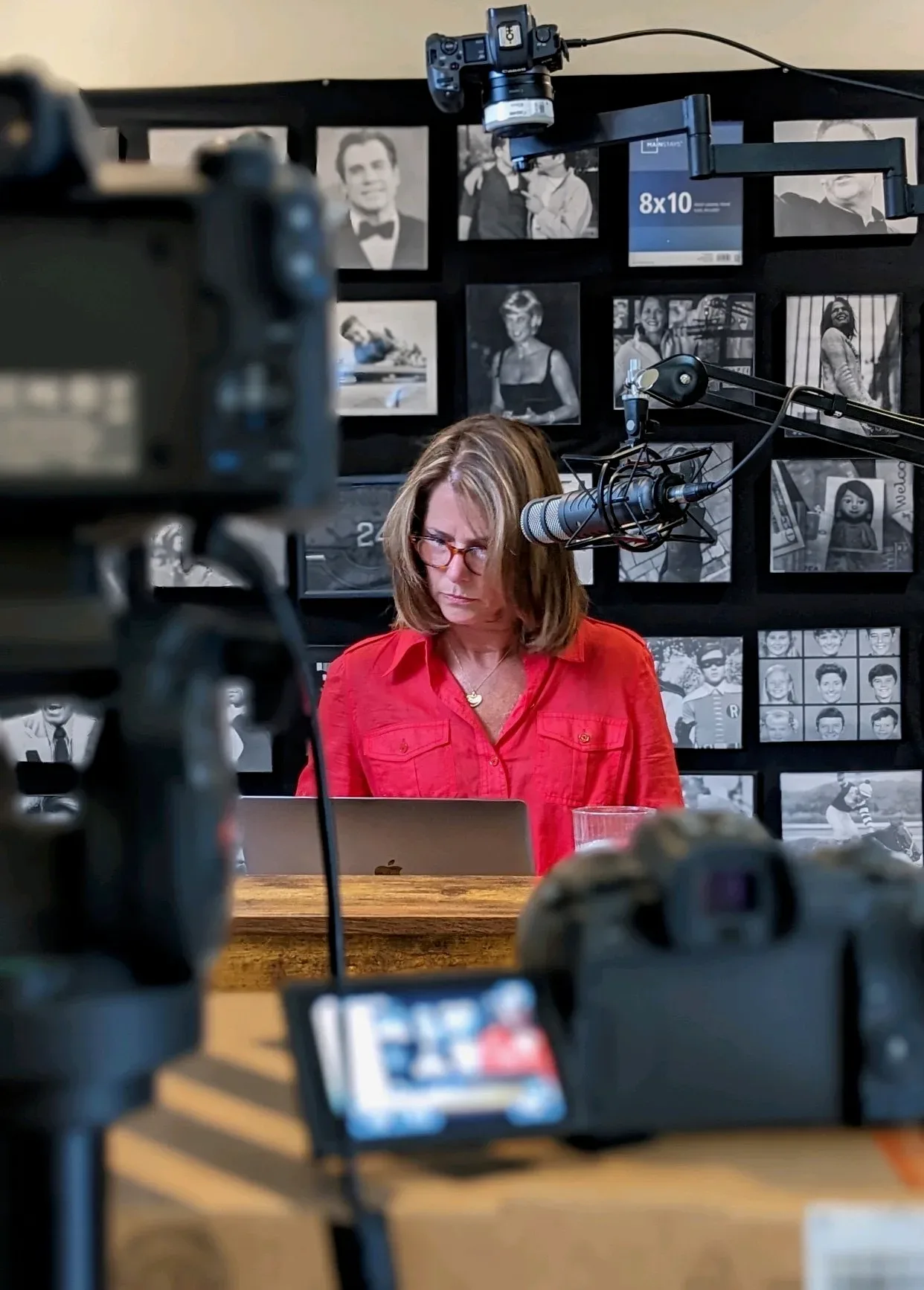 Sharon Glatz Scott working at her desk in a recording studio with professional cameras, microphone, and monitors