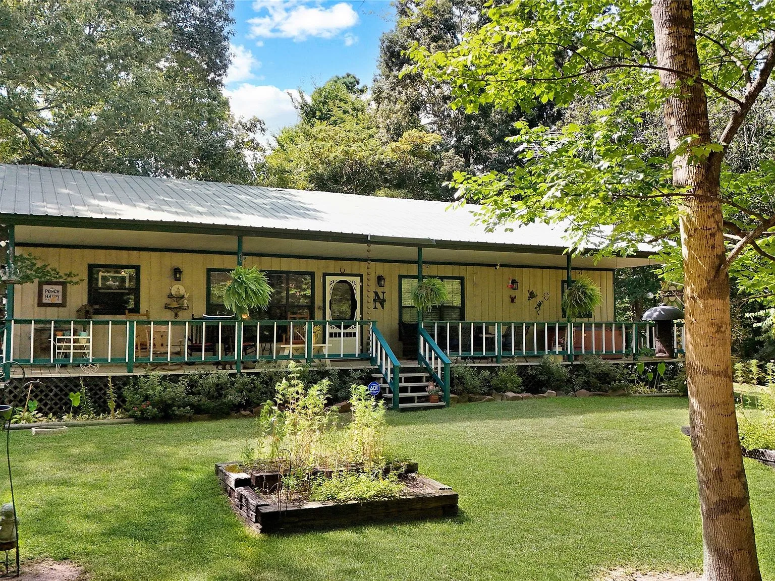 Covered front porch with ranch-style railing and mature trees