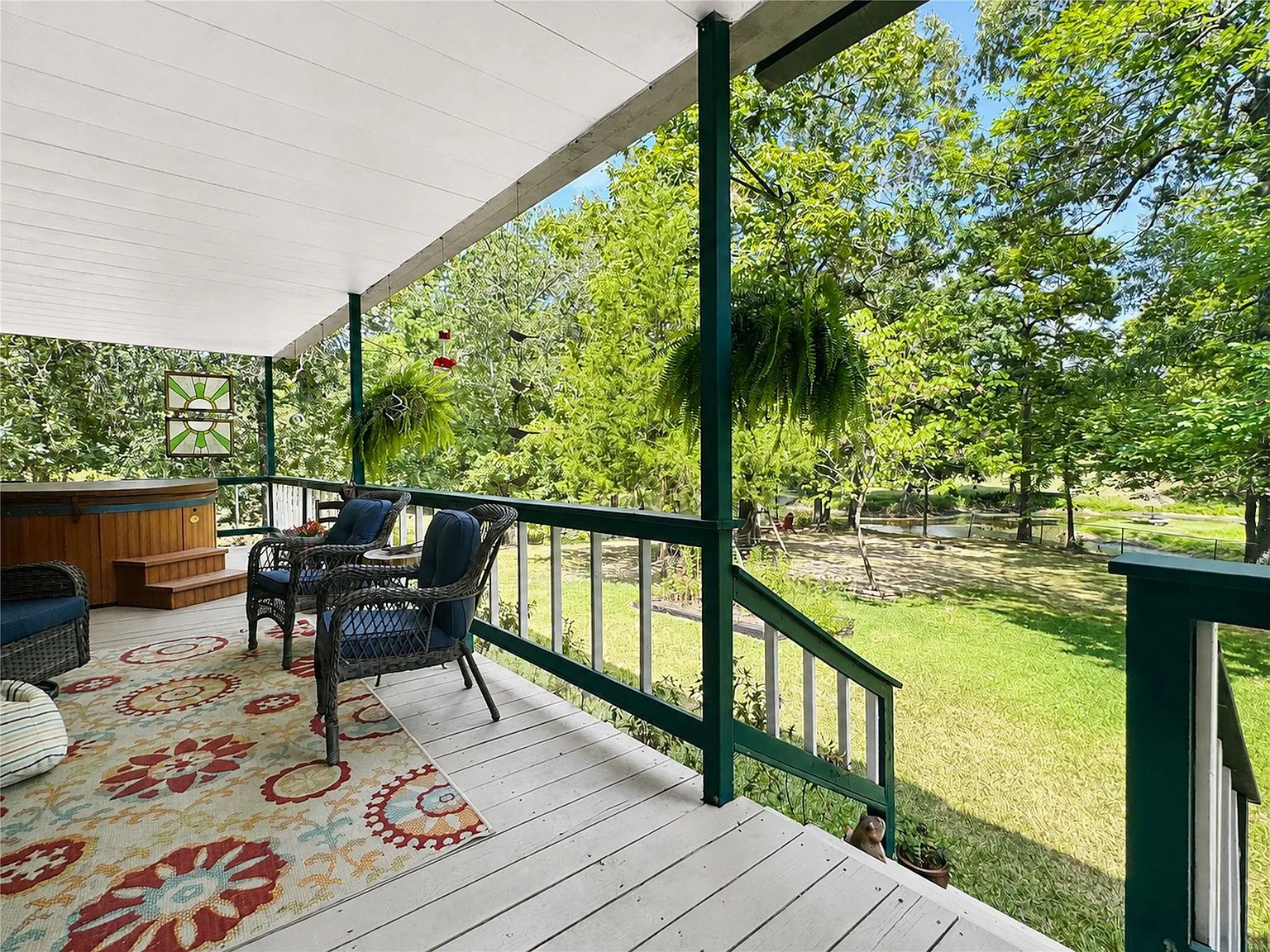 Covered porch overlooking the backyard with hot tub area