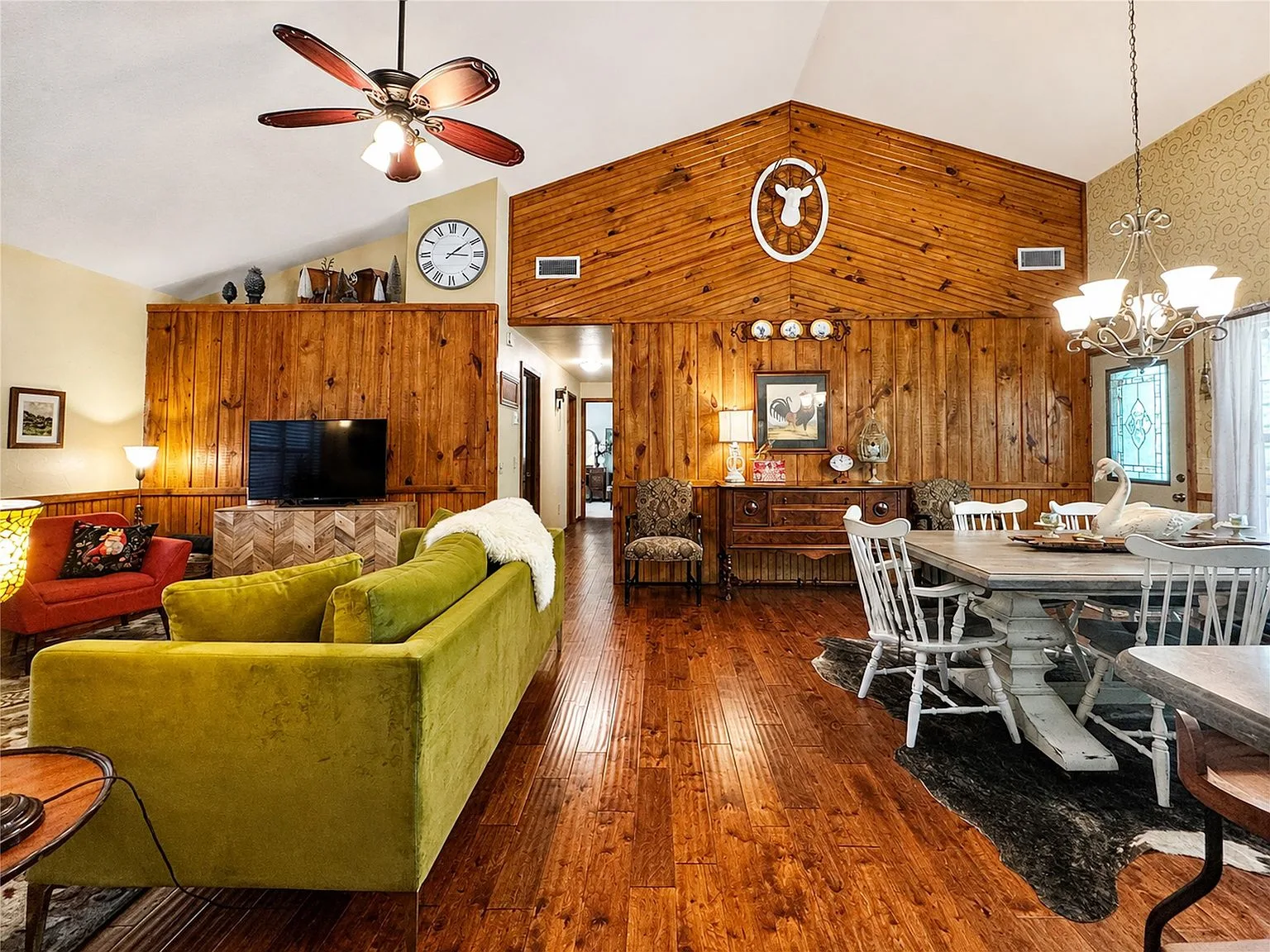 Open-concept living and dining room with pine wood-paneled walls