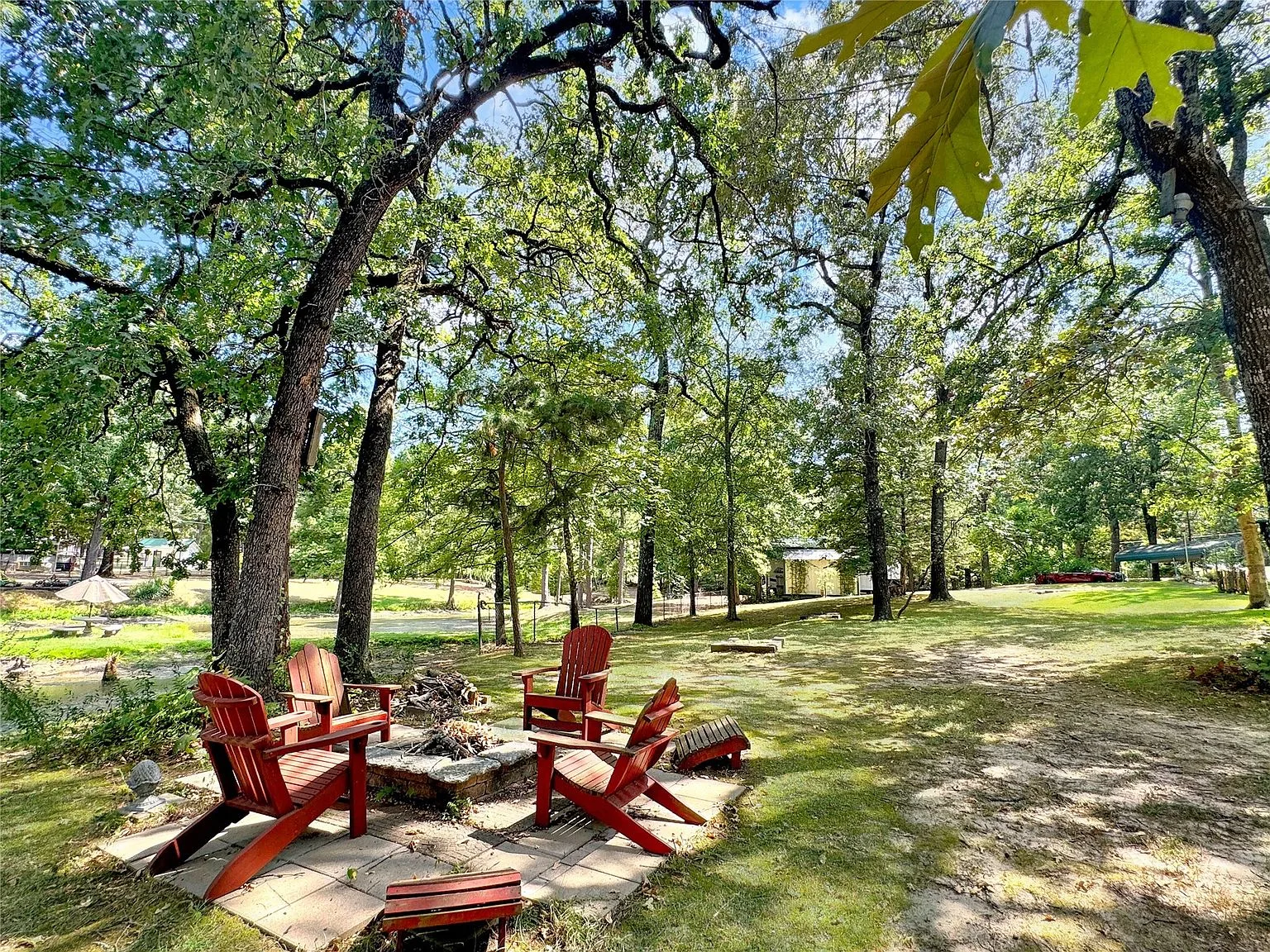 Wooded backyard with fire pit and Adirondack chairs