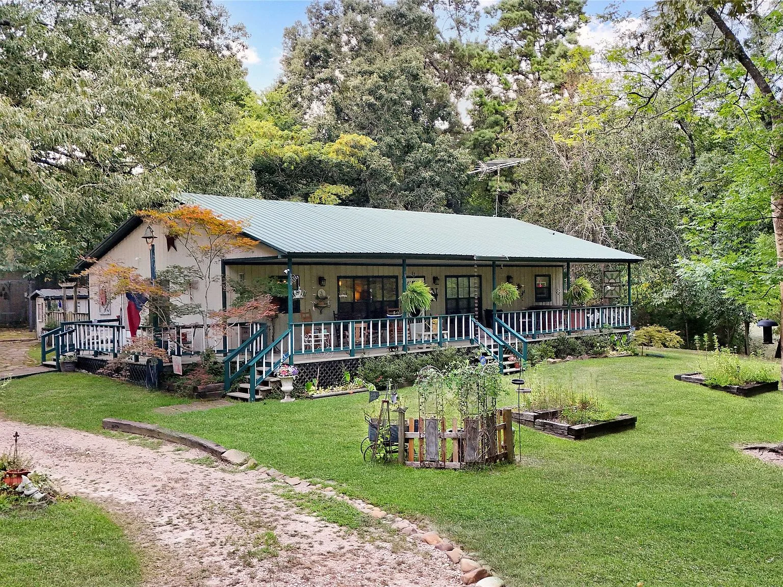 Full exterior facade of the ranch home with wrap-around porch and green metal roof