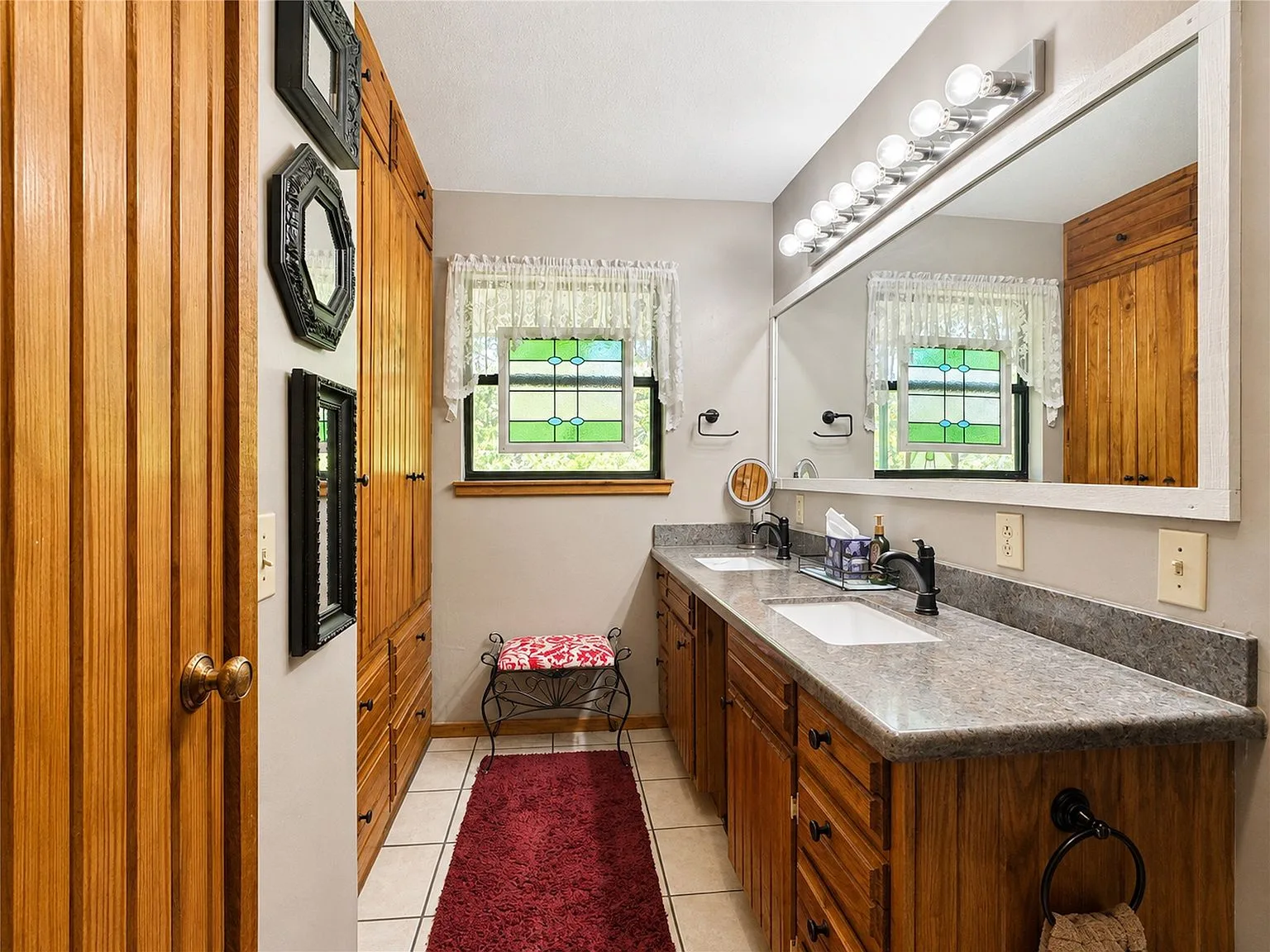 Bathroom with dual vanity and natural wood cabinetry