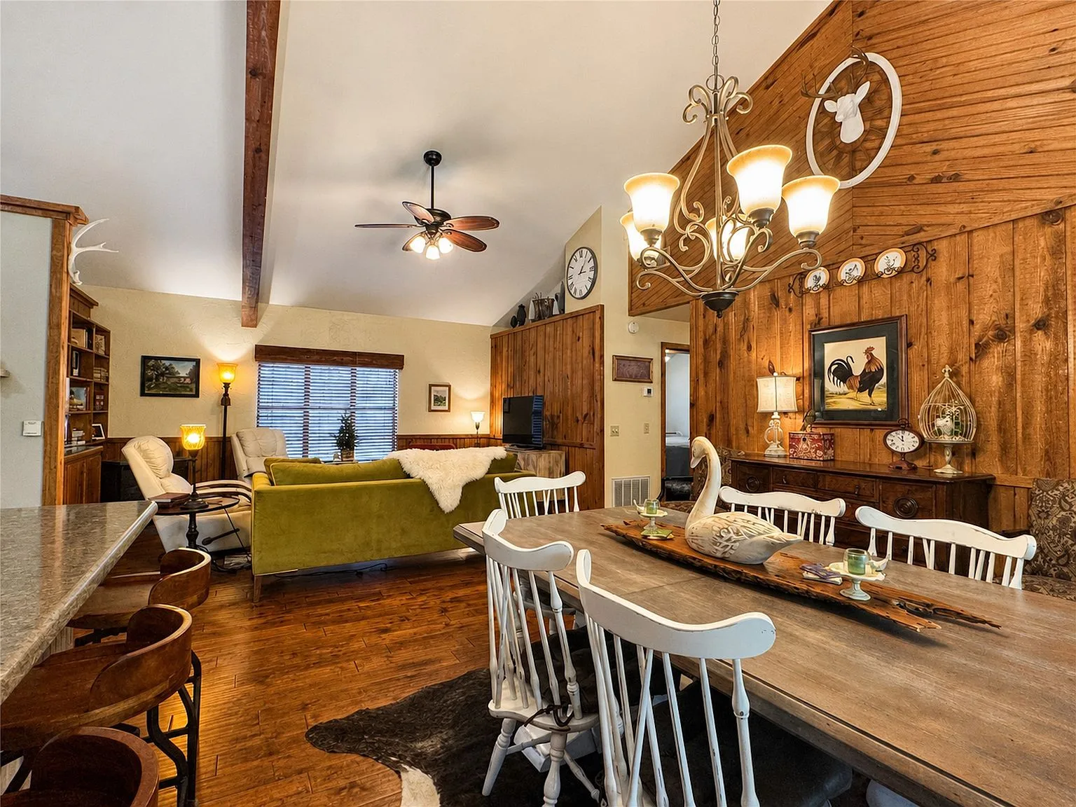 Rustic dining room and living area with wood paneling and hardwood floors