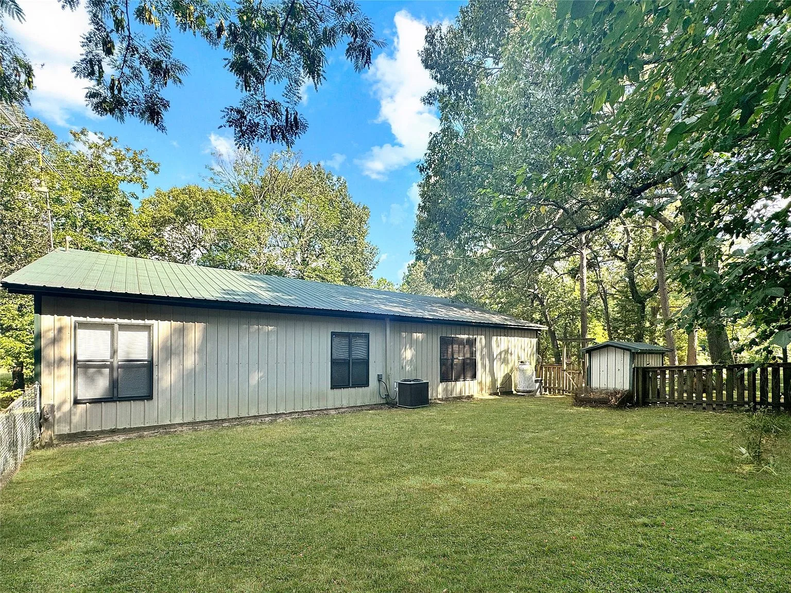 Rear exterior with vertical metal paneling and green metal roof
