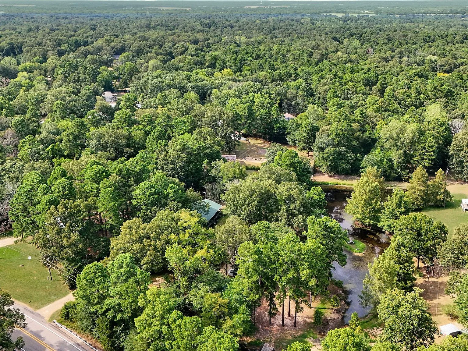 Aerial view of heavily wooded acreage with a winding creek