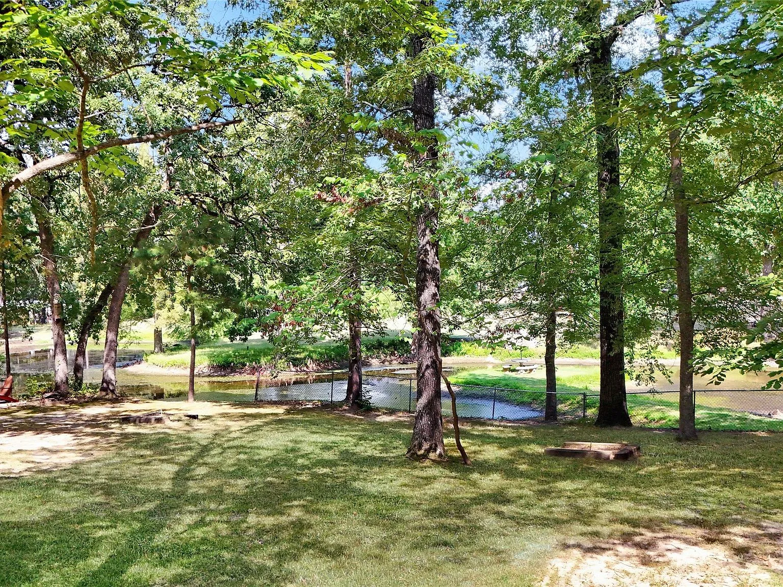 Backyard shot facing the creek through a chain-link fence