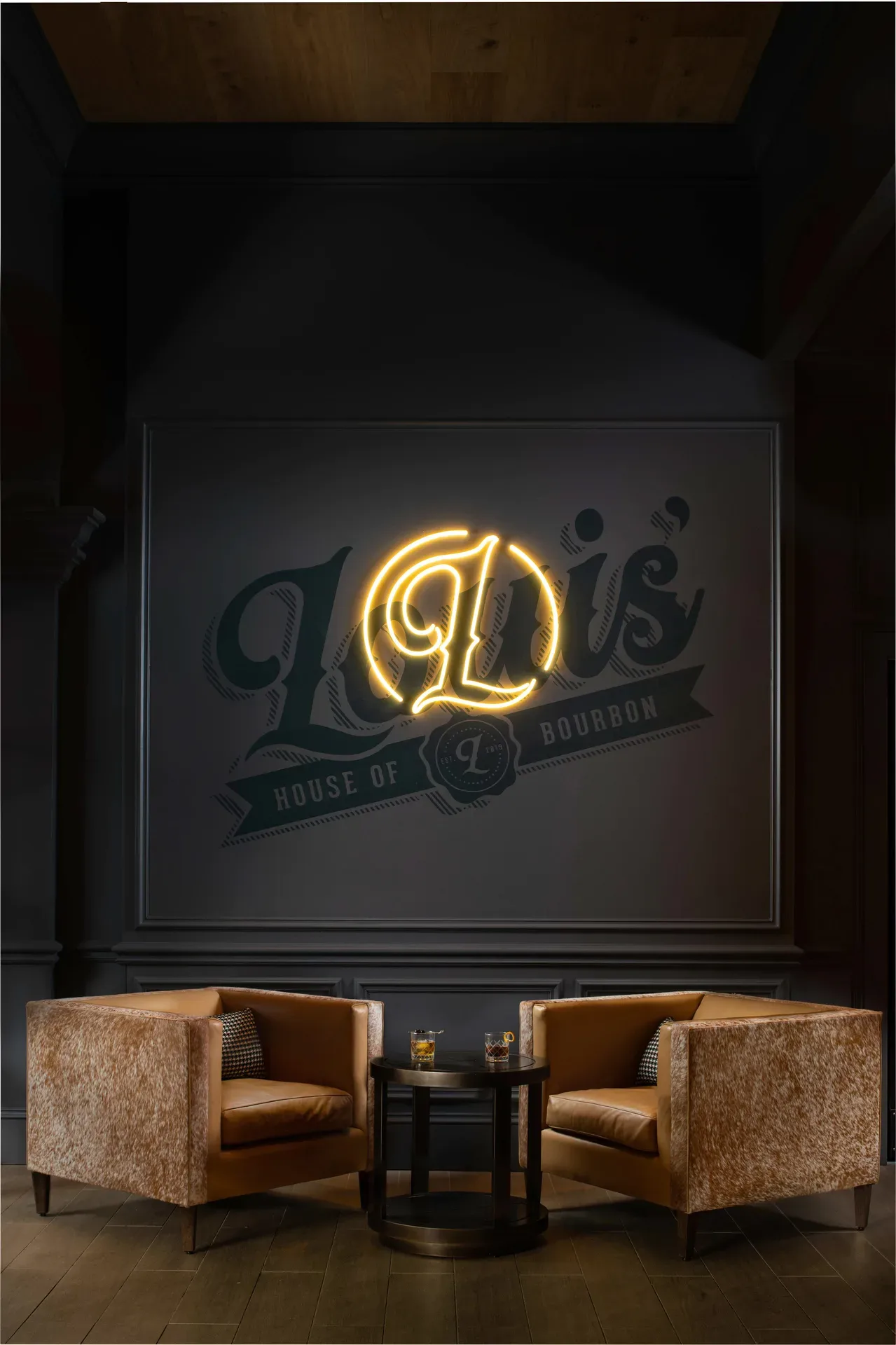 Sophisticated lounge seating area at Louis' House of Bourbon with dark matte walls, leather club chairs, and warm neon glow