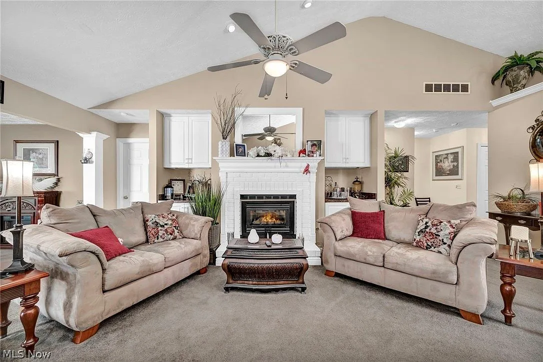 Great room with vaulted ceiling, white brick fireplace, and built-in cabinetry