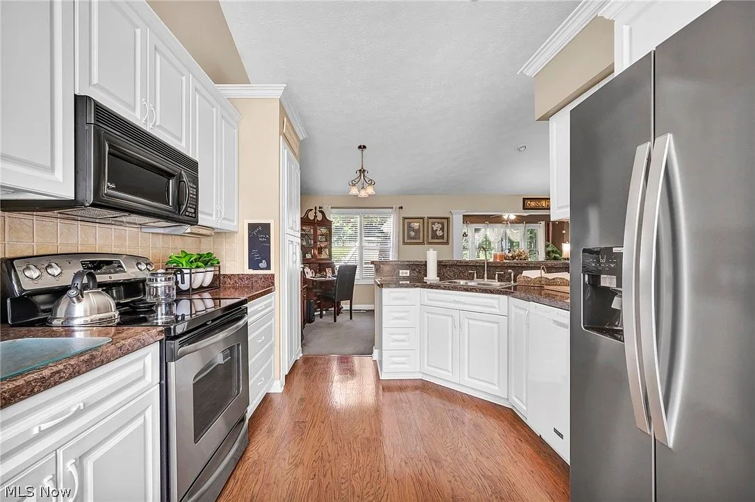 Kitchen with white cabinetry, granite countertops, and stainless steel appliances
