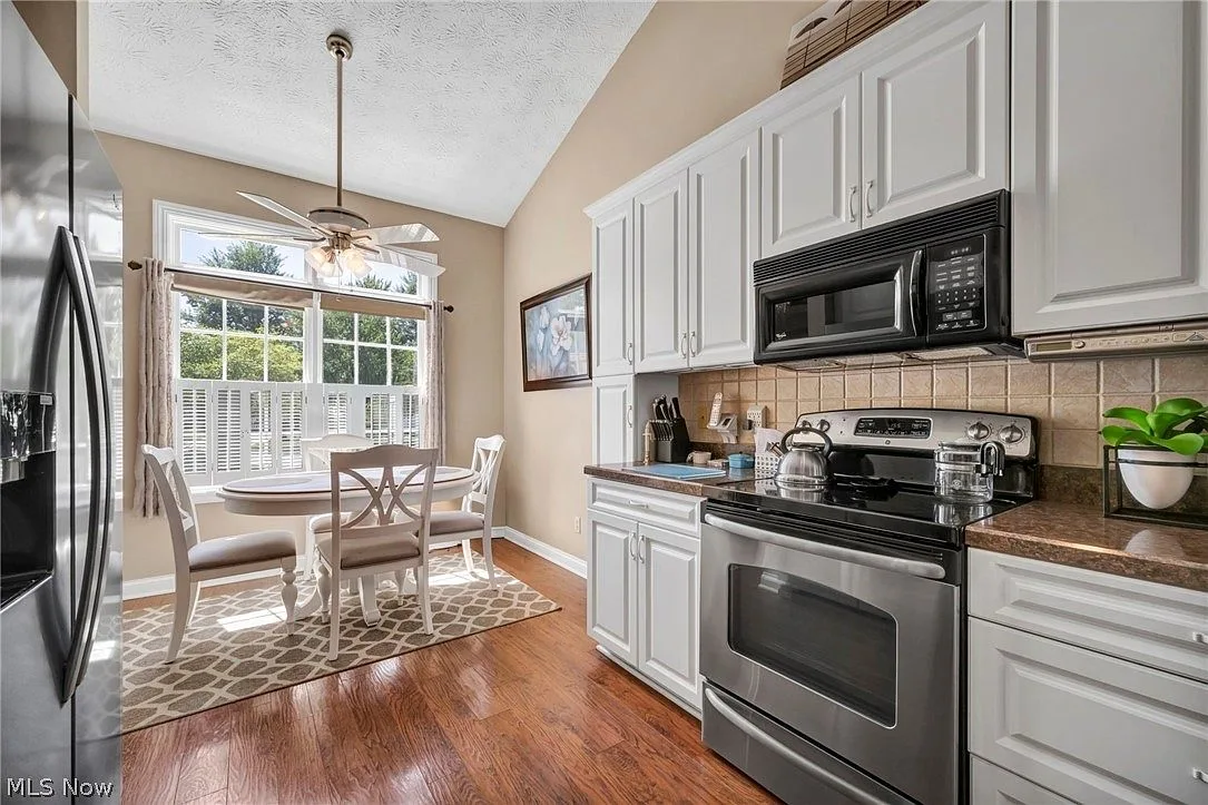 Eat-in kitchen with vaulted ceiling and white cabinetry