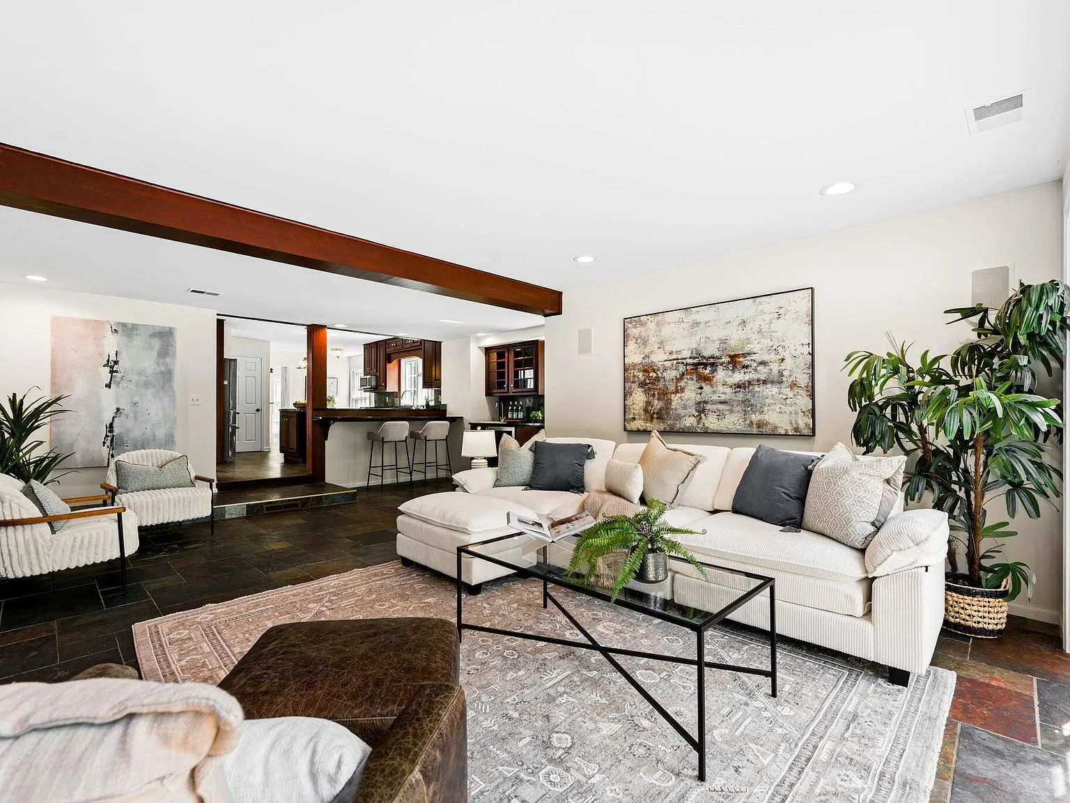 Living room with exposed structural wood beam and open flow into kitchen