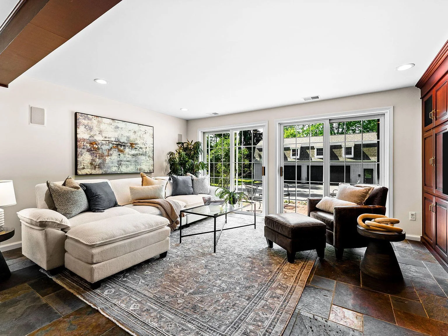 Living room with slate floor tiles, built-in dark wood cabinetry, and sliding glass doors