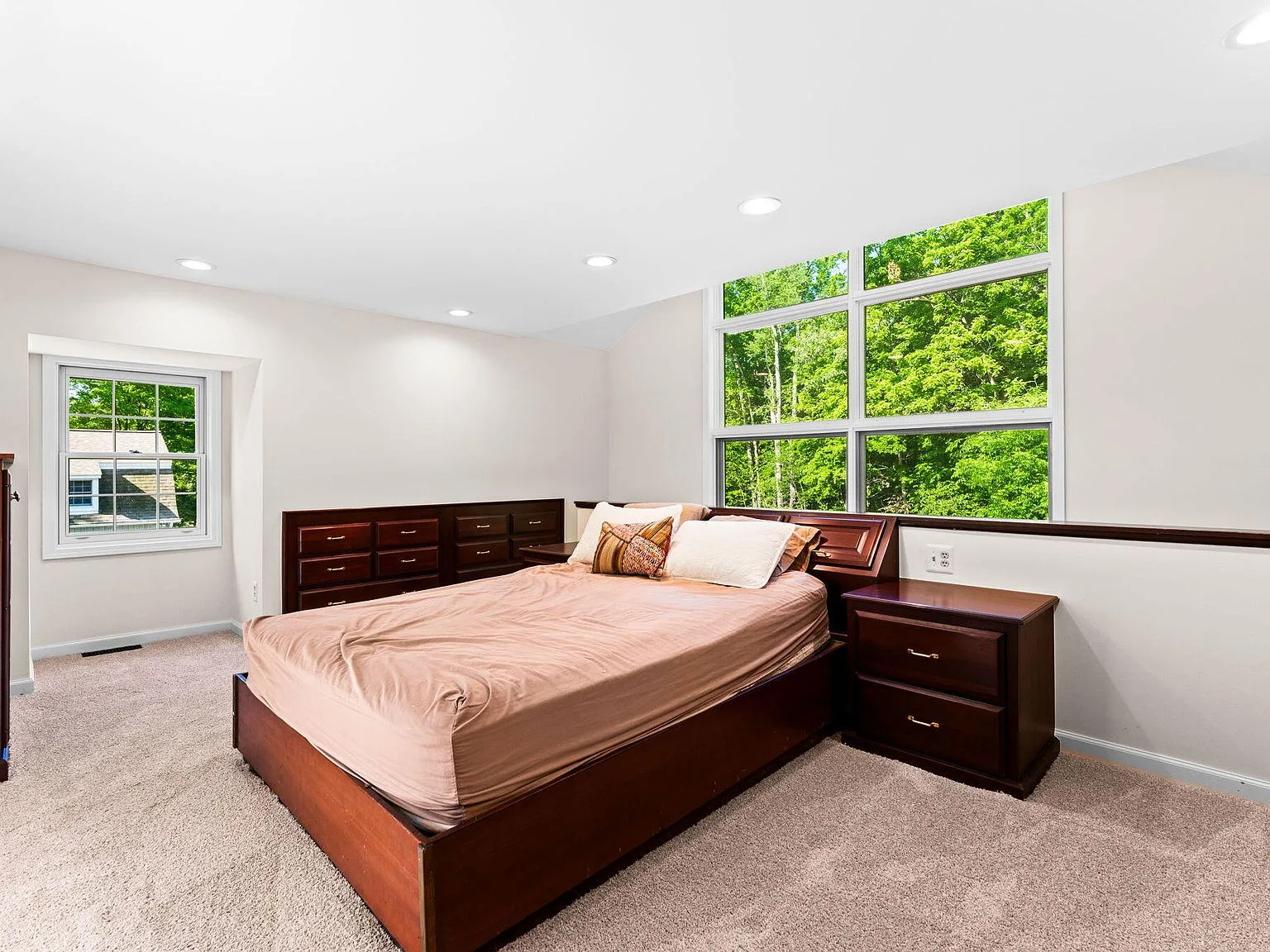 Bedroom with large window overlooking the green woodland
