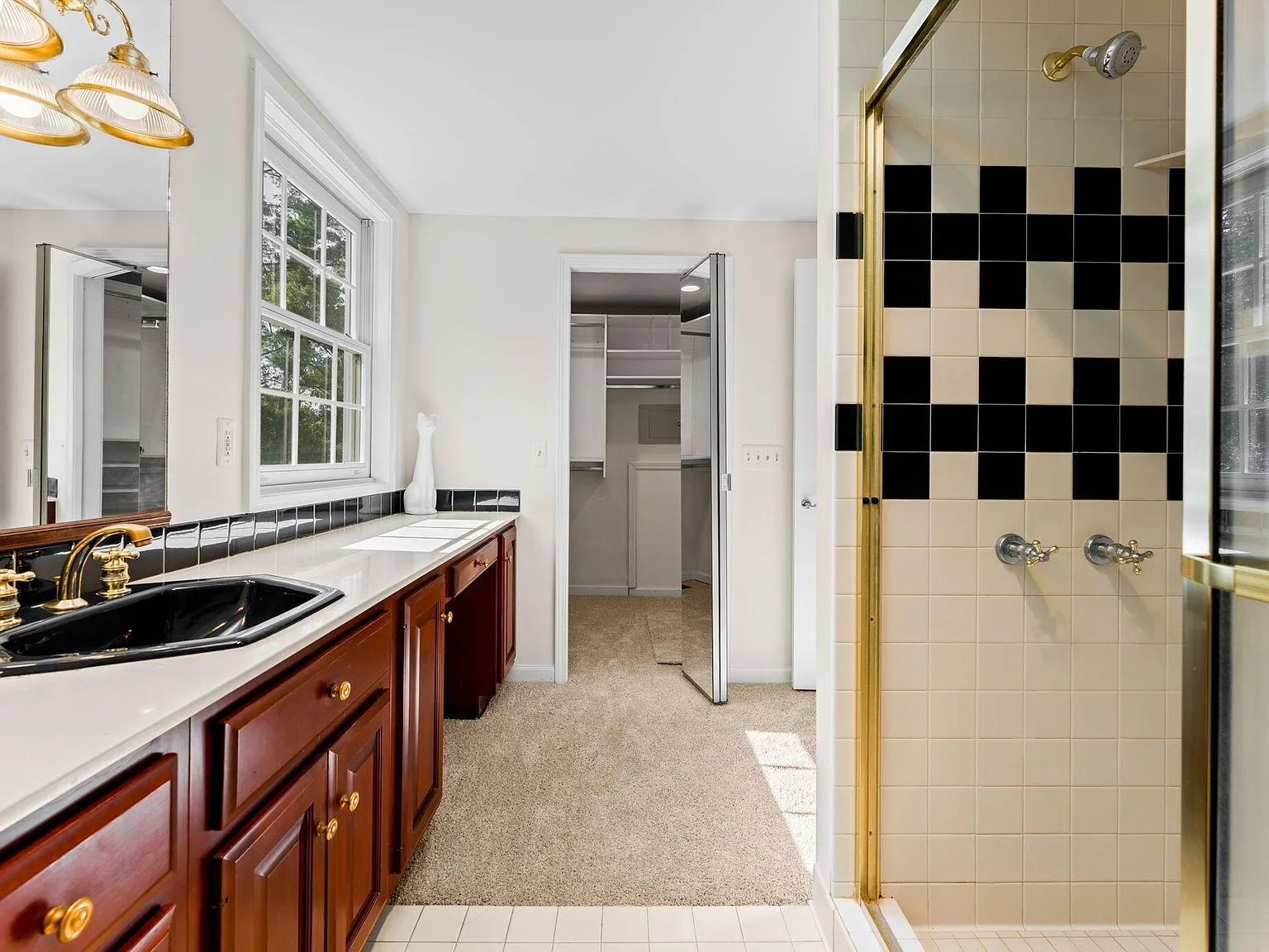 Primary bathroom with dark wood cabinetry and black-and-white tile shower