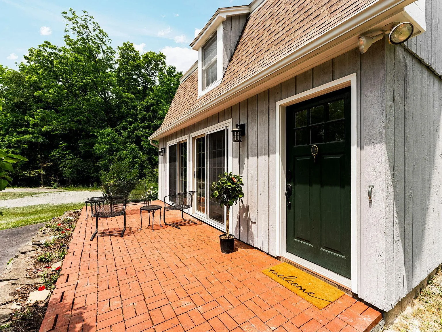 Carriage house entry with red brick patio and dark green door