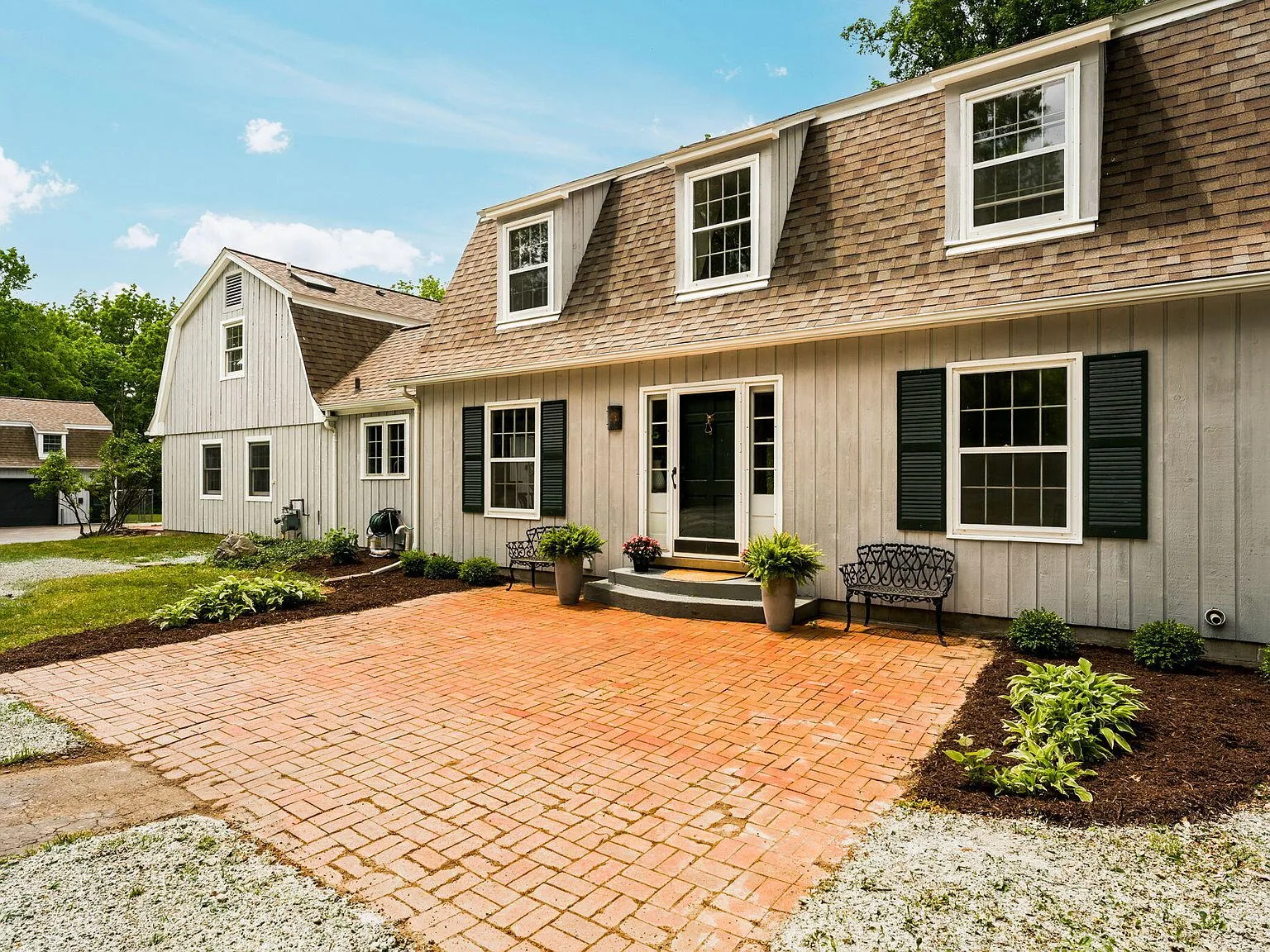 Front facade showing main house and partial view of carriage house with brick-paver patio