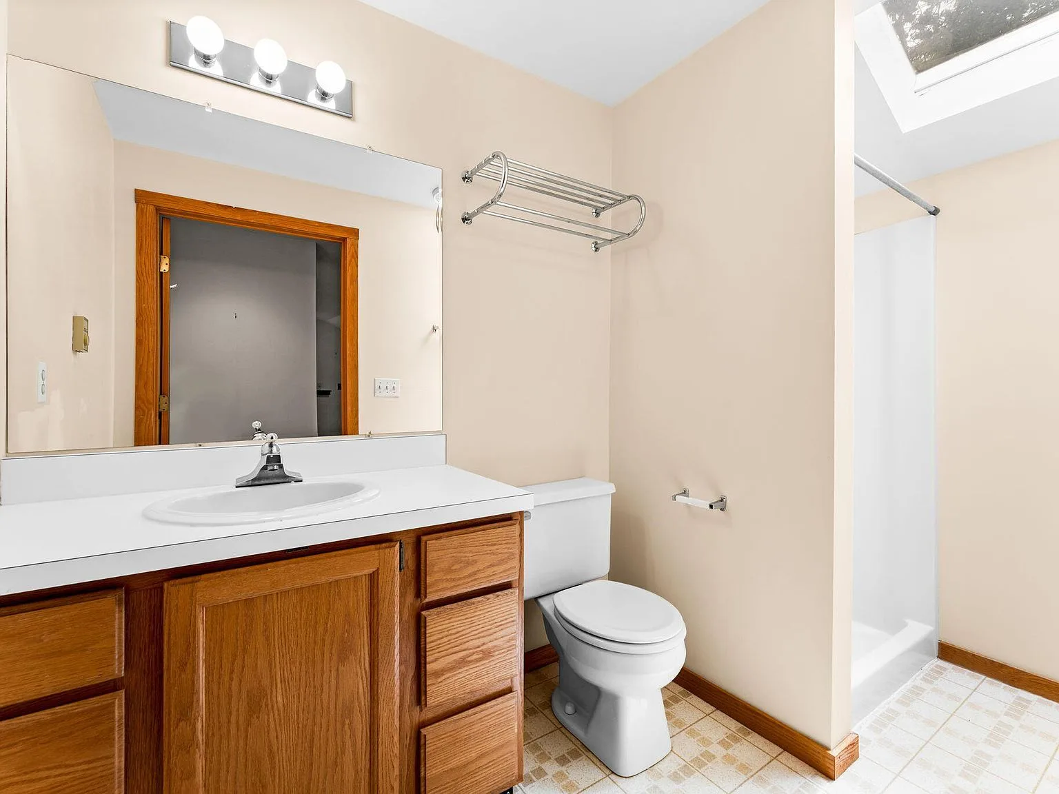 Bathroom with oak vanity and skylight over shower area