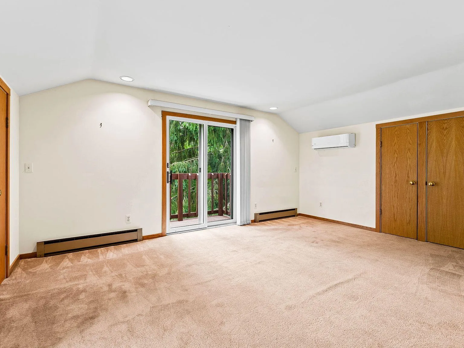 Carriage house bedroom with beige carpeting and sliding glass doors