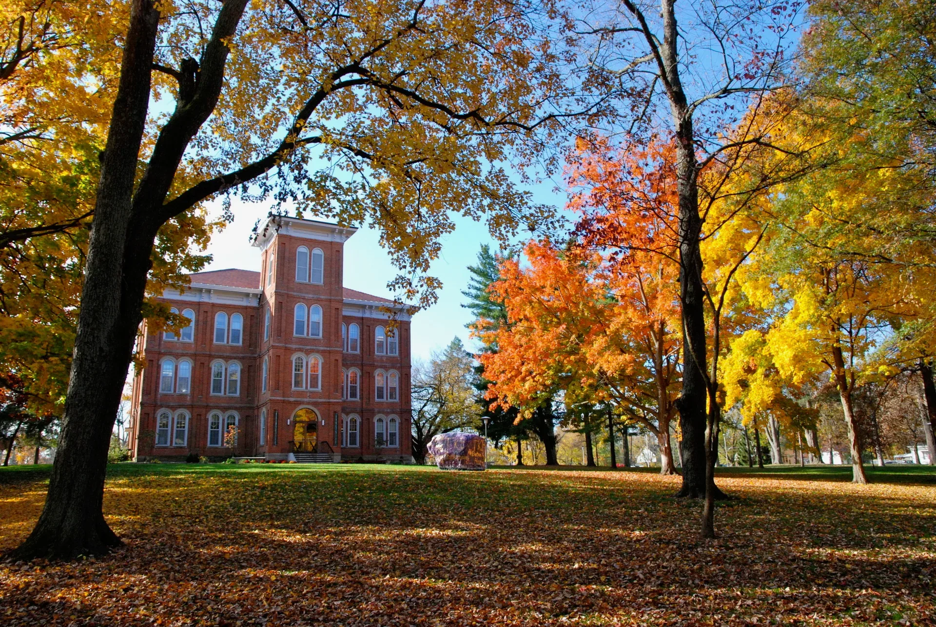 Historic brick facade of College Hall at Wilmington College in autumn, with warm fall foliage framing the building