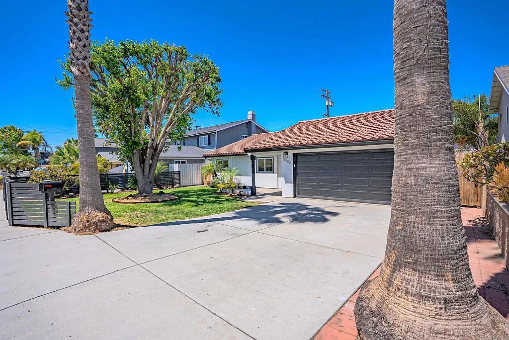 Coastal single-story home in Imperial Beach with stucco exterior, red tile roof, and palm trees in the front yard