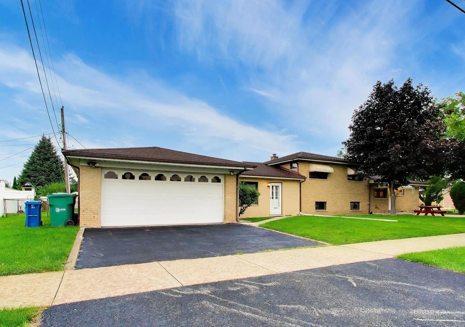 Brick split-level facade with white garage door and front lawn