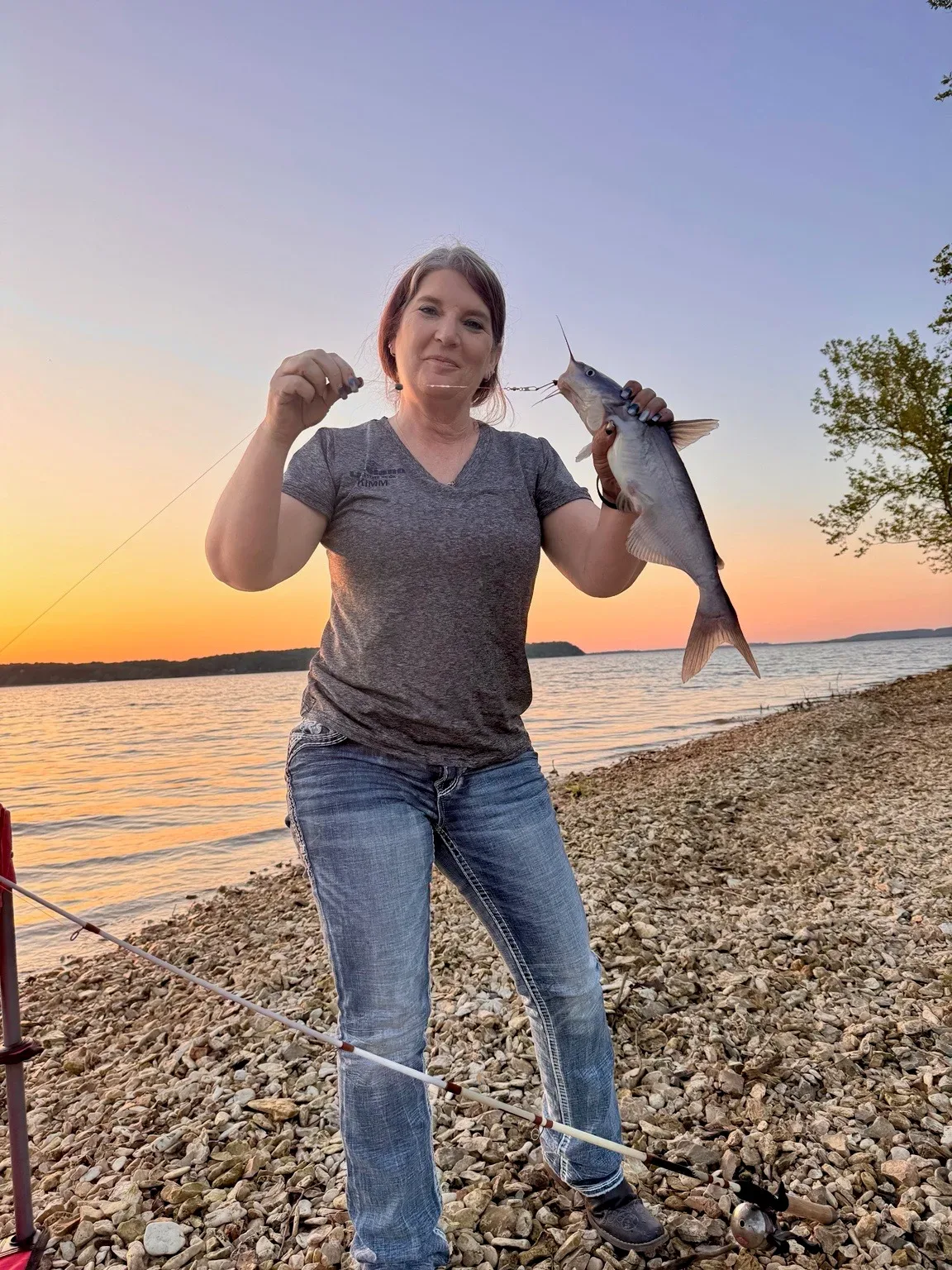 Kimm Kennon holding a catfish at sunset on Lake Hudson